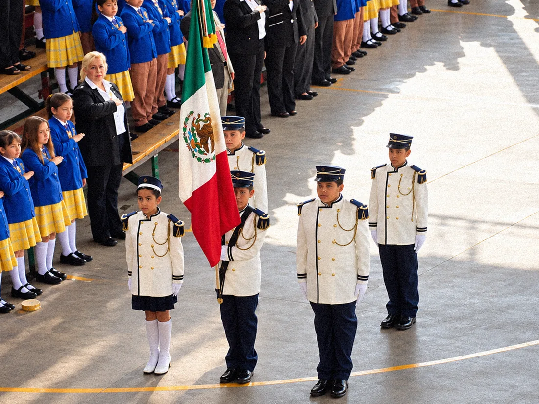 Escolta escolar con la bandera mexicana y estudiantes en formación